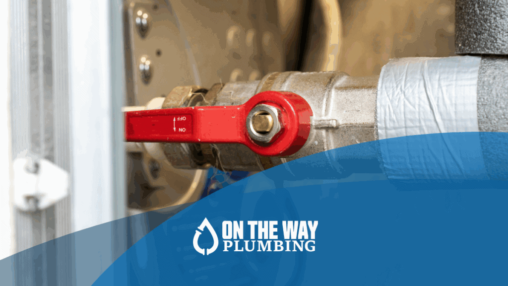 Close-up of a residential water shut-off valve with red handle in the off position, used to stop water flow during a plumbing emergency.