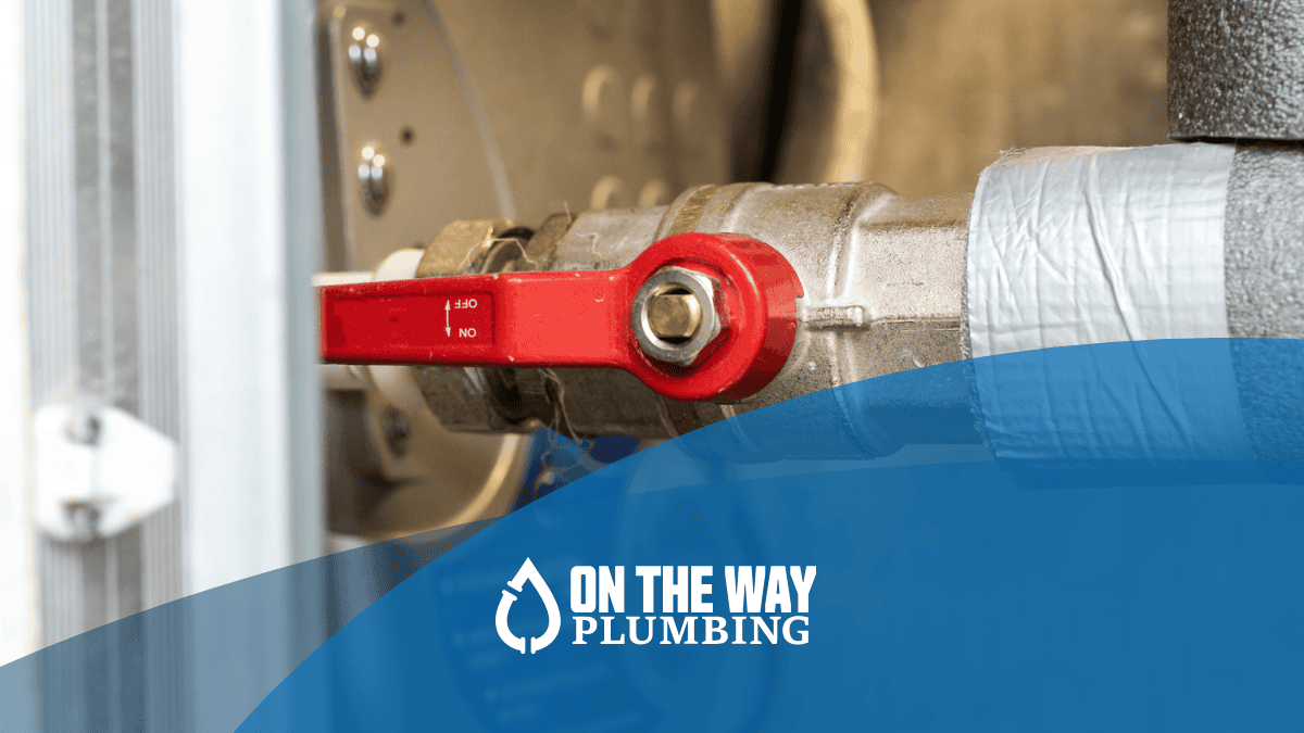Close-up of a residential water shut-off valve with red handle in the off position, used to stop water flow during a plumbing emergency.