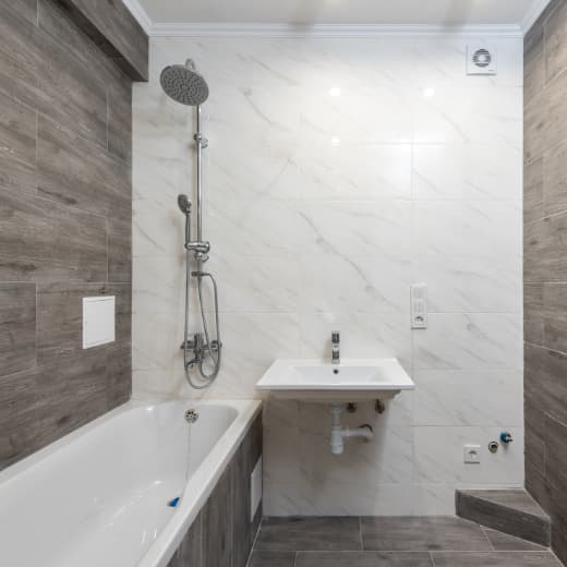 A sleek, modern bathroom with a new shower and sink being installed by On The Way Plumbing