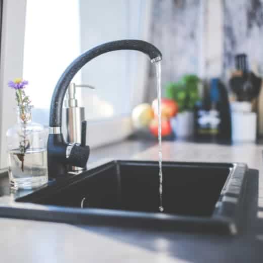 A kitchen sink with running water, showcasing a newly installed faucet by On The Way Plumbing