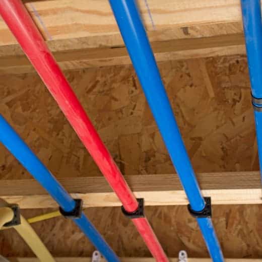 Freshly installed plumbing pipes running along a ceiling, showcasing a professional repiping job by On The Way Plumbing
